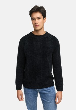 Schwarzer, gestrickter Pullover mit strukturiertem Finish, Rundhals und gerippten Bündchen. Getragen über einer hellblauen Jeans, die einen lässigen Schnitt zeigt.