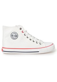 White high-top sneakers made of canvas with a round logo, red eyelets, and a white rubber sole featuring red and navy stripes.