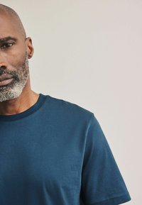 Camiseta de cuello redondo en azul marino, hecha de una tela suave, con mangas cortas y una sutil textura, con costuras bien terminadas en el cuello y las mangas.