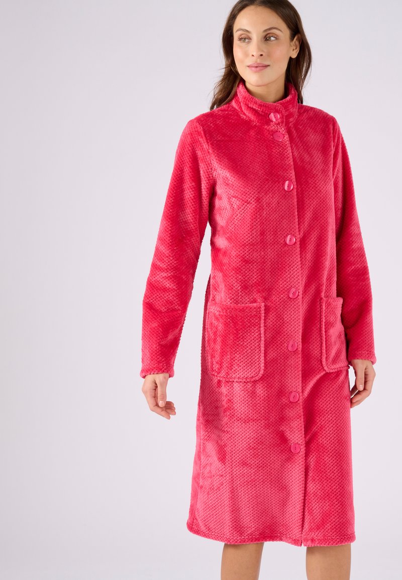 Abrigo largo de forro polar rosa con un cuello alto, botones en el frente y dos bolsillos de parche. Tejido texturizado con un acabado suave y un diseño ligero.