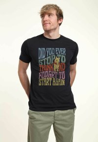 Black t-shirt featuring colorful text: “Did you ever stop to think and forget to start again” alongside an illustration of a bear.
