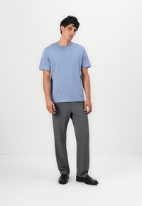 Tricou bleu deschis cu mânecă scurtă, asociat cu pantaloni gri, croiți, și pantofi negri. Ansamblul are o croială relaxată și texturi fine.