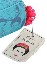 Borsa blu con facce illustrate e un'etichetta a forma di portachiavi che mostra il volto stilizzato di Frida Kahlo con corona di fiori e labbra rosse.