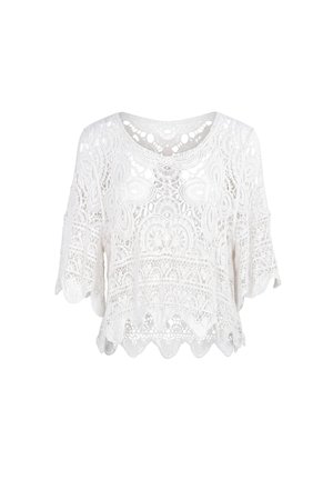 Blouse blanche en dentelle à manches courtes avec motifs floraux et géométriques, ourlet festonné et col rond.
