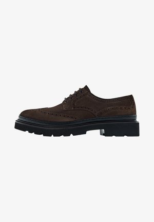 Chaussure brogue en daim brun foncé avec fermeture à lacets, détail à bout ailé, et semelle épaisse en caoutchouc noir à crampons.