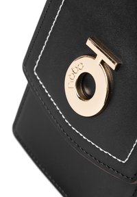 Schwarze Lederhandtasche mit goldfarbener, runder Hardware, die den Markennamen zeigt, sowie weißen Nähten entlang der Kanten.