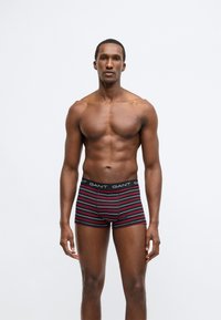 Férfi csíkos boxeralsó fekete, piros és fehér színekben. Rugalmas derékrész "GANT" logóval. Testhezálló, combközépig érő, puha és rugalmas anyagból készült.