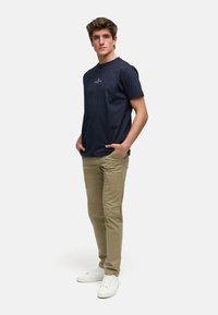 Marineblå bomull t-skjorte med rund hals, parret med beige chinos og hvite sneakers, som viser en avslappet passform og uformell stil.