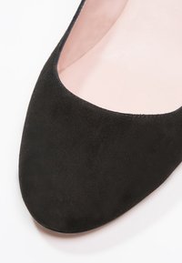 Schwarze Wildlederschuhe mit runder Zehenpartie, ausgestattet mit einem glatten Innenfutter und feinen Nähten entlang der Kanten.