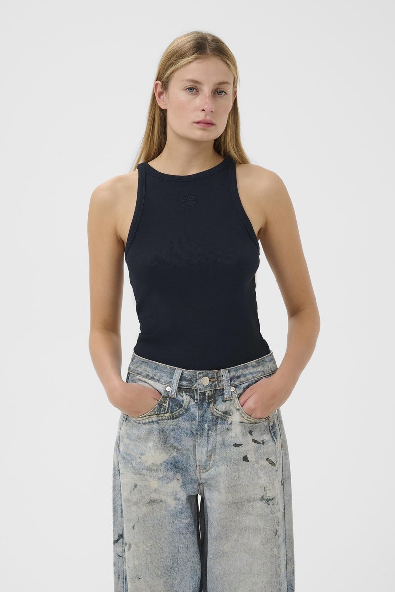 Canotta blu navy a coste con scollo alto, abbinata a jeans larghi azzurri strappati, con due tasche frontali e motivi sbiaditi.