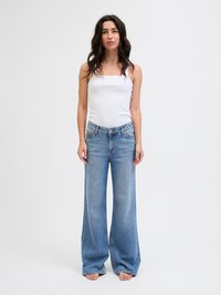 Blå vide jeans laget av denim, med høy midje, fem-lomme-design og en falmet, lett slitt finish. Kombinert med en hvit tanktop.