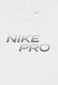 Hvit treningstopp med "NIKE PRO"-logo i svart prikket tekst. Har rund hals og myk, glatt tekstur.
