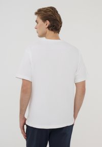 T-shirt bianco a maniche corte con colletto rotondo, realizzato in cotone. Presenta una vestibilità rilassata e un colore uniforme senza fantasie o accenti.