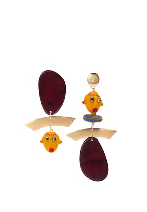 Asymetryczne kolczyki z abstrakcyjnymi żółtymi twarzami, czerwonymi ustami, złotymi zakrzywionymi prętami i ciemnofioletowymi owalnymi kształtami na białym tle.