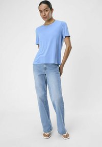 Camiseta de manga corta azul claro combinada con jeans rectos azul claro y sandalias blancas, con un ajuste relajado y una textura suave.