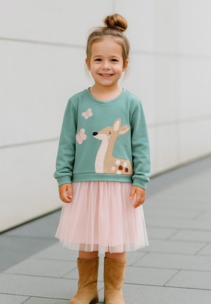 Hellgrüner Sweatshirt mit Bestickung von einem Reh und einem Schmetterling, kombiniert mit einem rosa Tüllrock und beigen Ankle Boots.