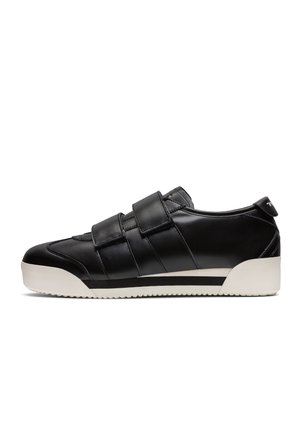 Czarny niski sneaker z dwoma szerokimi paskami na rzepy i białą gumową podeszwą z czarnym paskiem wzdłuż boku.