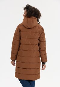 Bruine pufferjas met een capuchon, voorzien van horizontale stiksels en geribbelde manchetten. Glad textuur, knielange ontwerp en ontspannen pasvorm.
