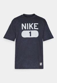 Marineblå kortærmet t-shirt lavet af bomuld, med et stort hvidt trykt "NIKE" logo og tallet "1" på forsiden.