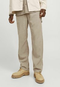 Beige corduroy broek met een rechte pijpdesign; gladde textuur met verticale ribbels; gedragen met lichtbruine schoenen.