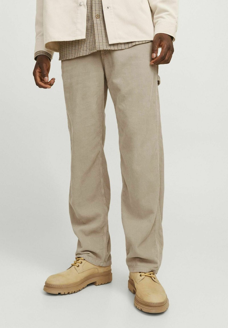 Beige corduroy broek met een rechte pijpdesign; gladde textuur met verticale ribbels; gedragen met lichtbruine schoenen.