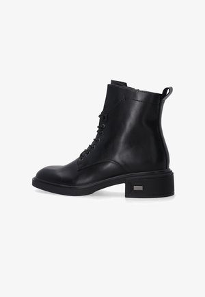 Černá kožená kotníková bota s kulatou špičkou, šněrováním vpředu a nízkým řemínkovým podpatkem. Obsahuje poutko na zadní straně a strukturovaný detail po stranách.