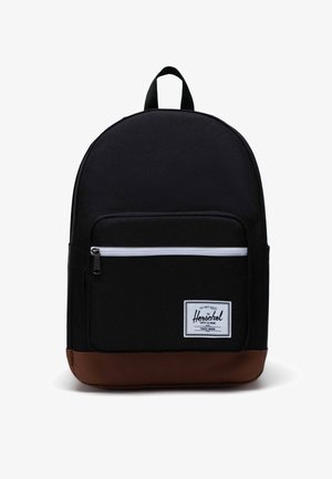 Schwarzer Rucksack mit braunem Boden, ausgestattet mit einer vorderen Reißverschlusstasche und einem weißen Streifen. Hergestellt aus strapazierfähigem Material, runder Form und mit abnehmbarem Tragegriff.