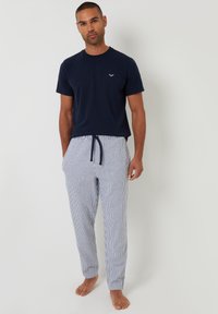 T-shirt di cotone blu navy abbinata a pantaloni da pigiama a righe blu e bianche, con vita elastica e cordoncino.