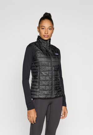 Vestă neagră fără mâneci izolantă, cu model matlasat orizontal, fermoar frontal, guler tip în picioare și buzunare laterale. Potrivită pentru a fi purtată peste alte haine.