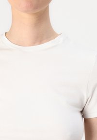 Hvit bomulls T-skjorte med rund hals, korte ermer og en glatt, tettsittende tekstur. Minimalistisk design uten mønstre eller detaljer.