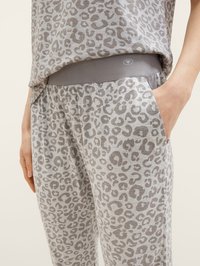 Grå leopardmönstrad loungedräkt med en lös passform överdel och byxor med elastiskt midjeband. Mjukt tyg, avslappnad silhuett och sidfickor.