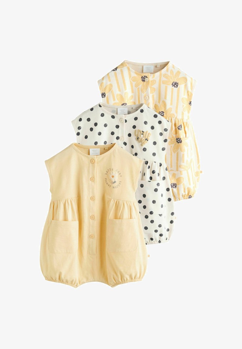 Tri bezrukávové detské overalové body: jeden žltý s grafikou a vreckami, jeden biely s čiernymi bodkami a jeden kvetinový s výraznými pruhmi.