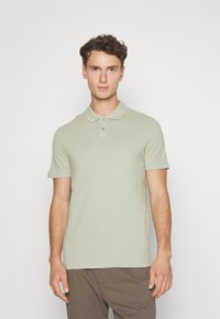 Polo shirt in lichtgroene katoen, met een kraag, twee knoopsluitingen en korte mouwen. Glad textuur en getailleerde silhouet.