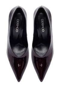 Une paire de chaussures à talons aiguilles pointues, laquées d'un bordeaux sombre, avec des semelles intérieures noires portant l'étiquette "DERIMOD", vue de dessus.