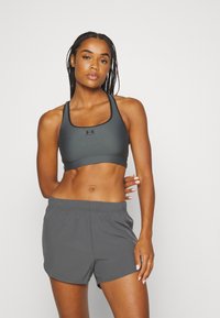 Donkergrijs sportbeha met een ronde halslijn en lichte padding, gecombineerd met bijpassende lichte shorts met een elastische tailleband.