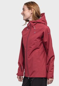 Rote wasserdichte Jacke mit Kapuze, ausgestattet mit einem Frontreißverschluss, Schnürdetails und belüfteten Einsätzen. Glatte Textur mit sportlichem Design.