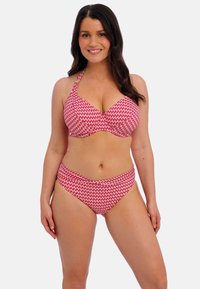 Bikini set s halter topem a vysokými kalhotkami v červené barvě s bílým cik-cak vzorem; měkká tkanina, podpůrný design.