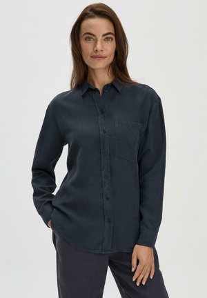 Camisa azul oscuro de botones con mangas largas, bolsillo en el pecho y dobladillo curvado. Fabricada en un suave tejido texturizado.