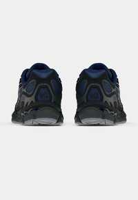 Μαύρα και μπλε αθλητικά παπούτσια με πλέγμα στην επάνω πλευρά, υφασμάτινα πάνελ, μαξιλαρωτή σόλα και λάστιχο στο κάτω μέρος για πρόσφυση.