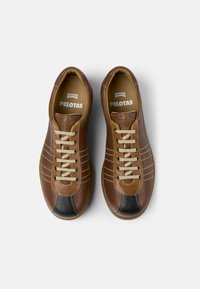 Sneakers in pelle marrone con una punta nera a contrasto, lacci beige, cuciture decorative e una superficie testurizzata. Marchio sulla soletta.