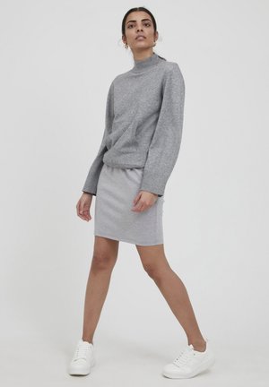 Sweatshirt gris clair avec un col montant et des manches longues, associé à une jupe ajustée assortie. Des baskets blanches complètent la tenue.