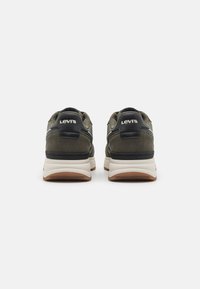 Zapatillas de ante verde con acentos en negro y suelas blancas. Presenta un logo en el talón y un acabado texturizado. Diseño de punta redondeada.