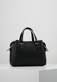 Mustan nahkainen käsilaukku, jossa on rakenteellinen muoto, kaksinkertaiset yläkahvat ja hopeanväriset varusteet sivuilla. Rakenne on teksturoitu.