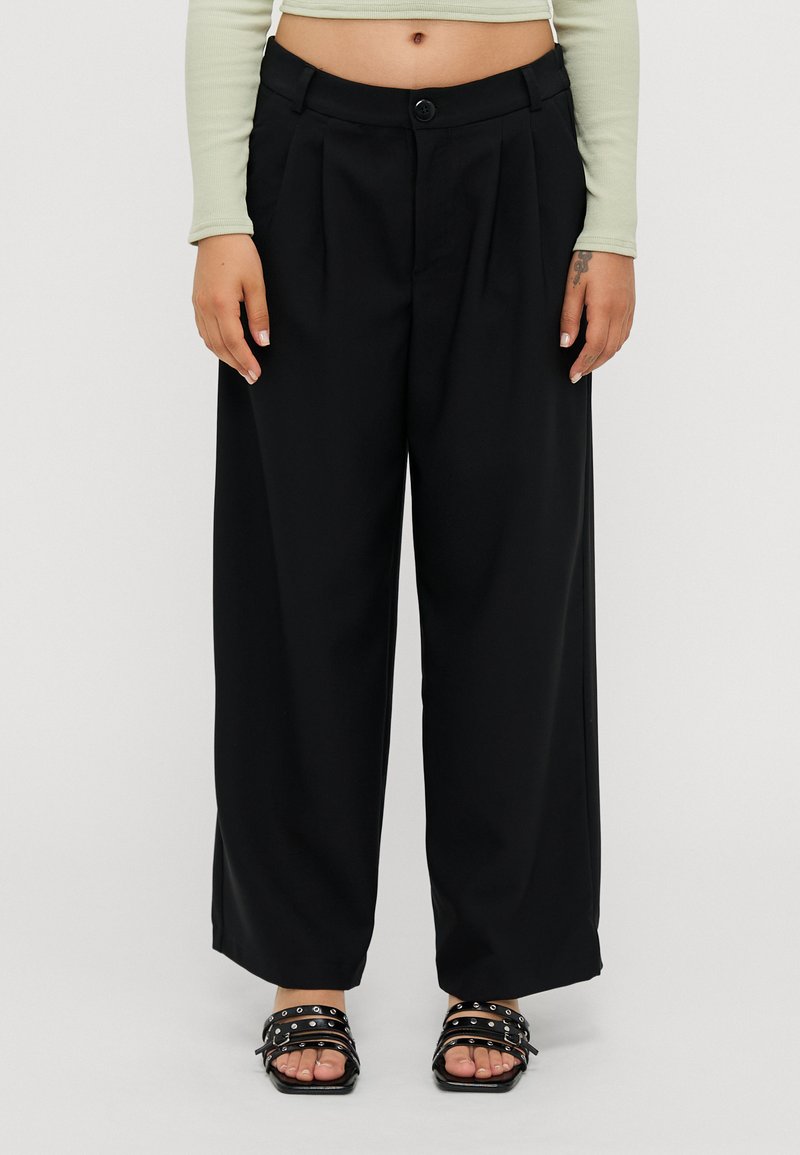 Black wide-leg trousers with pleats, featuring a button closure and a smooth fabric. Worn with black strappy sandals.