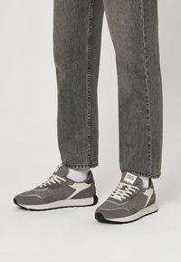 Baskets grises en feutre et en maille avec des accents blancs. Dotées d'un bout arrondi, d'un système de laçage et d'une semelle en caoutchouc.