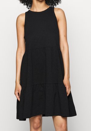 Zwarte mouwloze jurk van lichtgewicht stof, met een uitlopende rok met gelaagd ontwerp en zachte textuur. Eenvoudige ronde halslijn.