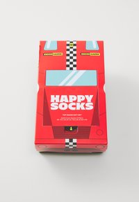 Piros, téglalap alakú doboz, amely versenyautóra emlékeztet, sakkmintázattal, nagy ablakokkal és vastag, fehér betűkkel írva: "HAPPY SOCKS".