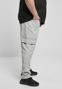 Hellgraue Cargo-Hose mit mehreren Taschen, aus strapazierfähigem Stoff, mit lockerem Schnitt und leicht zulaufendem Bein.
