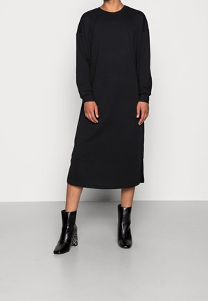 Czarna sukienka z długim rękawem wykonana z miękkiego materiału, z okrągłym dekoltem i bocznymi rozcięciami. W zestawie czarne botki do kostki z fakturowanymi akcentami.