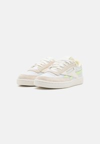 Beige mockasin och vita lädersneakers med pastellblå och gröna accenter, rund tå, sydda detaljer och struktur gummisula.